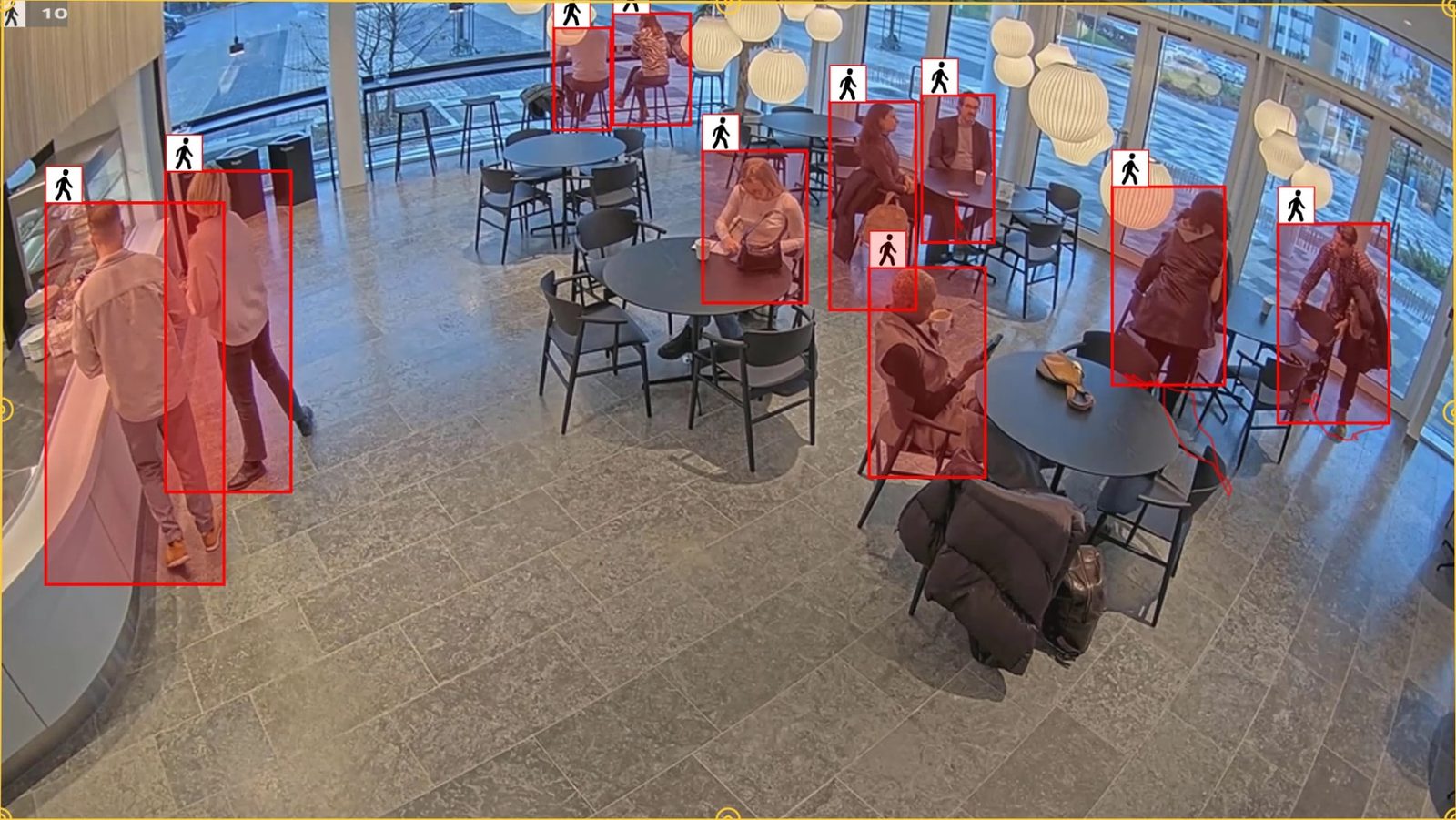 Computer vision detecting every person in a busy café and lobby space, drawing a box around each for occupancy and traffic analytics.